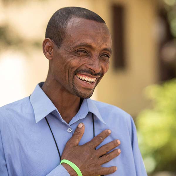 An African man laughing by putting his hand on heart
