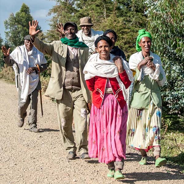 A group of three men, and three African women are going to somewhere, and they are smiling towards the camera