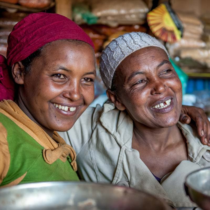 Two African women smiling by holding hands on each other's shoulders