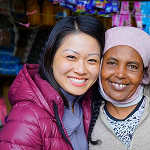 an old African woman with an Asian woman smiling while posing for a picture.
