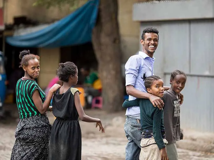 Young African guy smiling and posing for a picture along with African kids