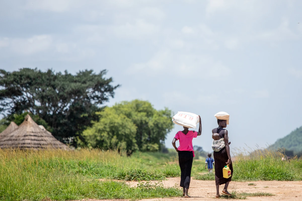 Two women and a baby in South Sudan carry emergency relief flour and oil that was gift by Petros Network partners through the local church.
