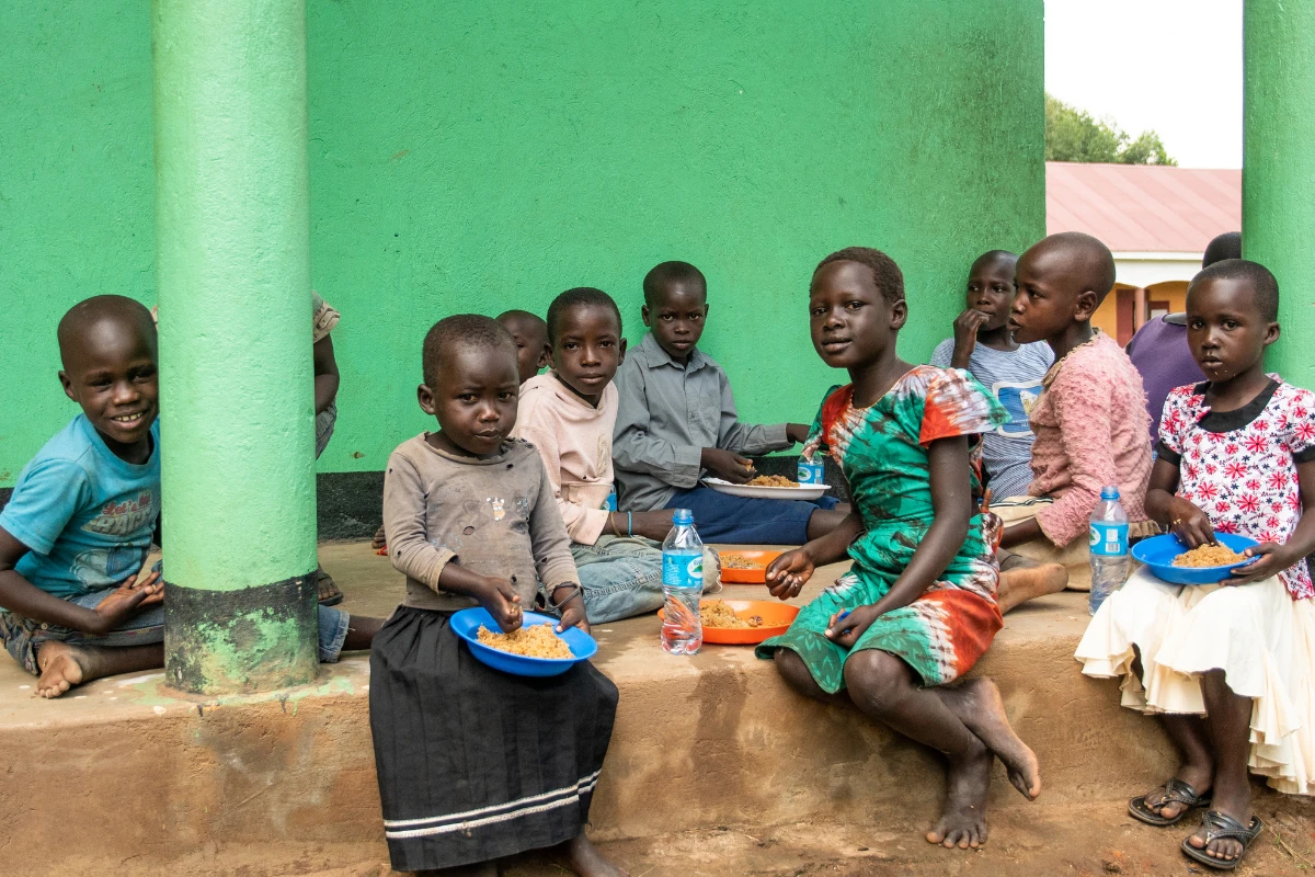 Children sitting around on the floor, eating.