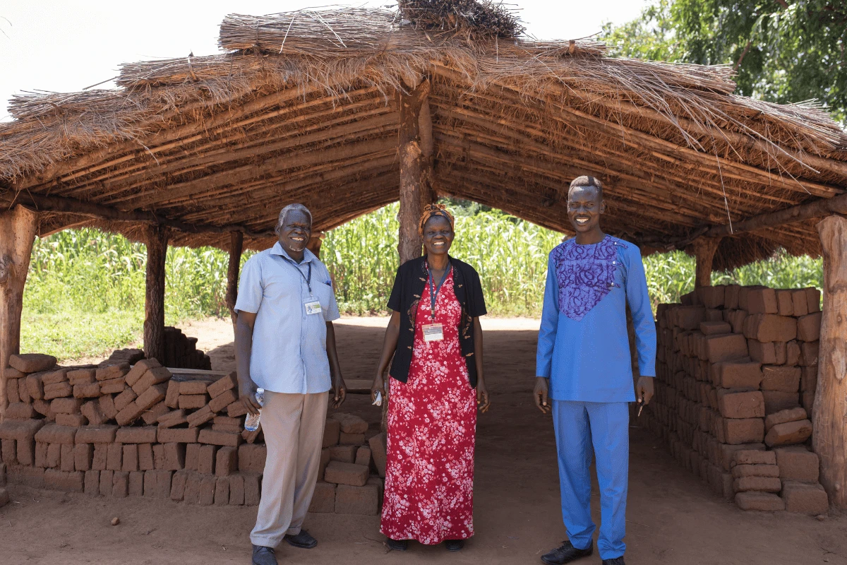 Three individuals posing outside Beatrice's garden